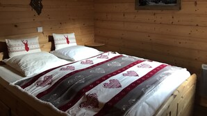Una habitación de cabaña de madera con una cama que tiene un edredón estampado y dos almohadas con motivos de renos.