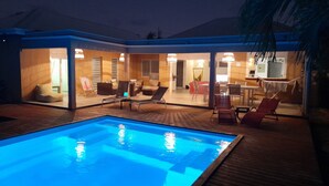 Une piscine avec des chaises longues et un espace repas.