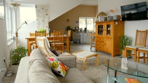 A spacious living area with a sofa, chairs, a dining table, and a kitchen in the background. - Exclusive Holiday Apartment with Moselle View & Bike Garage (Bullay)