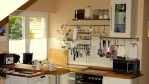 A compact kitchen with a microwave, toaster, and coffee maker on the counter, a small refrigerator, and a window with a view of greenery. - Exclusive Holiday Apartment with Moselle View & Bike Garage (Bullay)