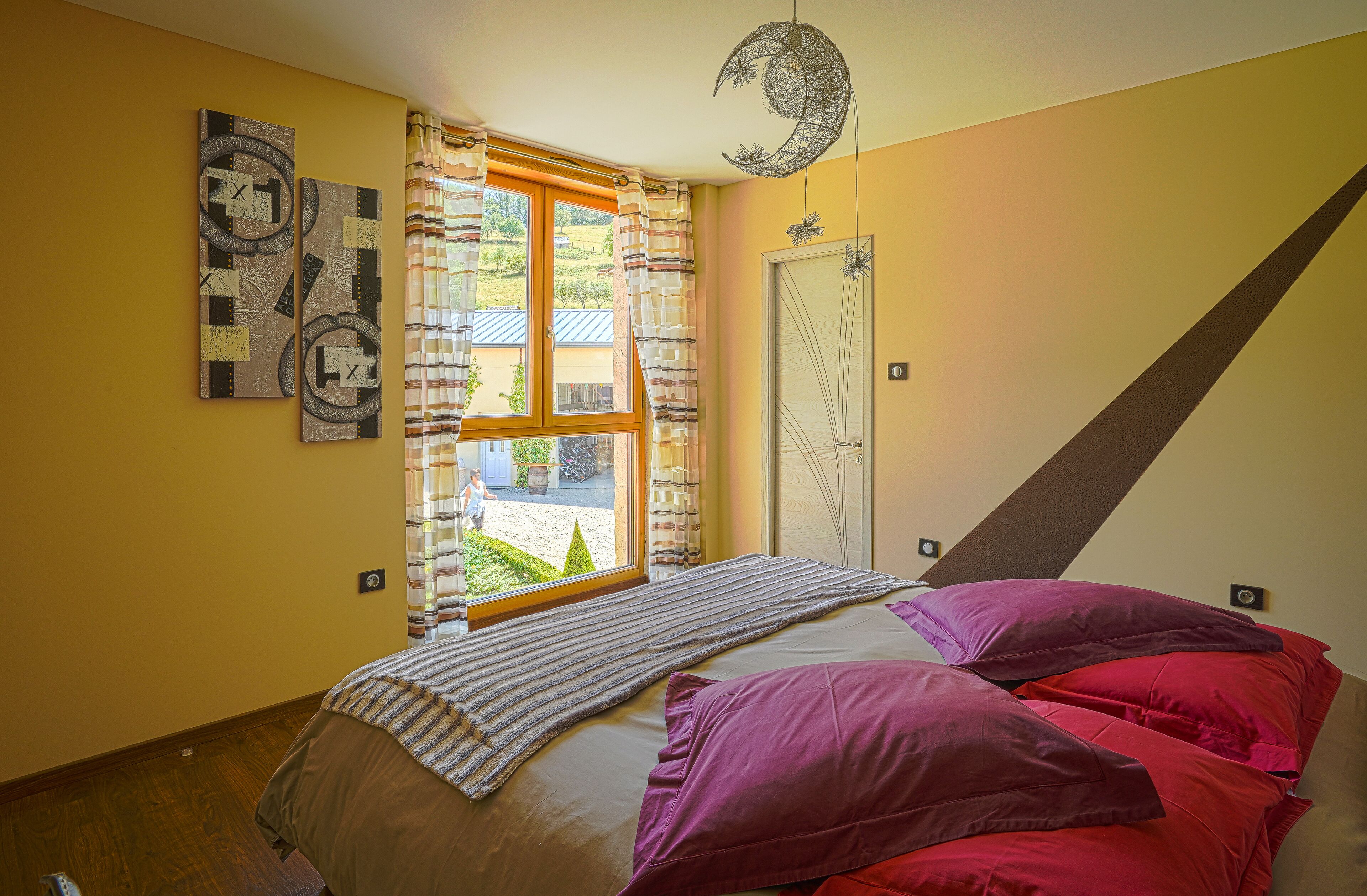 Ein Schlafzimmer mit einem Bett, einem Fenster mit Vorhängen, einer Wanduhr und einer Tür.