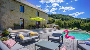 A stone building with a pool, outdoor seating, and a mountain backdrop. - 5-star villa with a pool available from August 29 to September 5 (Sainte Eulalie d'Olt)