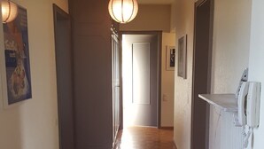 A hallway with wooden flooring, a ceiling light, and a door at the end. - Aviva (95 m2 apartment with terrace) (Huningue)