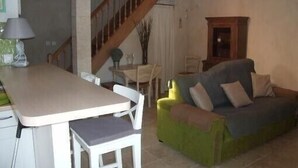 Una sala de estar con un sofá, una mesa de comedor y una escalera.