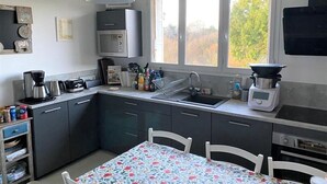 Eine moderne Küche mit Essbereich, ausgestattet mit einer Mikrowelle, einer Kaffeemaschine und einem Spülbecken.