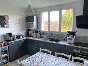 A modern kitchen with a dining area, featuring a microwave, coffee maker, and a sink.