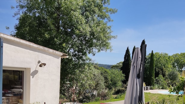 An outdoor patio with wicker furniture, a stone table, and a large planter. - Villa in the countryside near Aix-en-Provence town center (Aix-en-Provence)