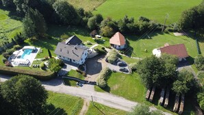 Una vista aerea di una zona residenziale con una grande casa, una piscina e un piccolo edificio con tetto rosso.
