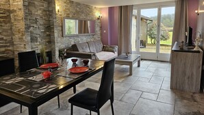 Un coin repas avec un mur en pierre, un canapé et une table dressée pour quatre personnes.