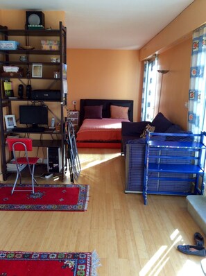 A bedroom with a bed, a desk, a computer, and a bookshelf.