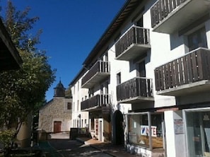 Un immeuble à plusieurs étages doté de balcons, d’une façade en pierre et surplombant un ciel d’un bleu limpide.