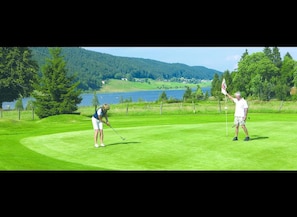 Un parcours de golf avec un lac et des collines en arrière-plan.