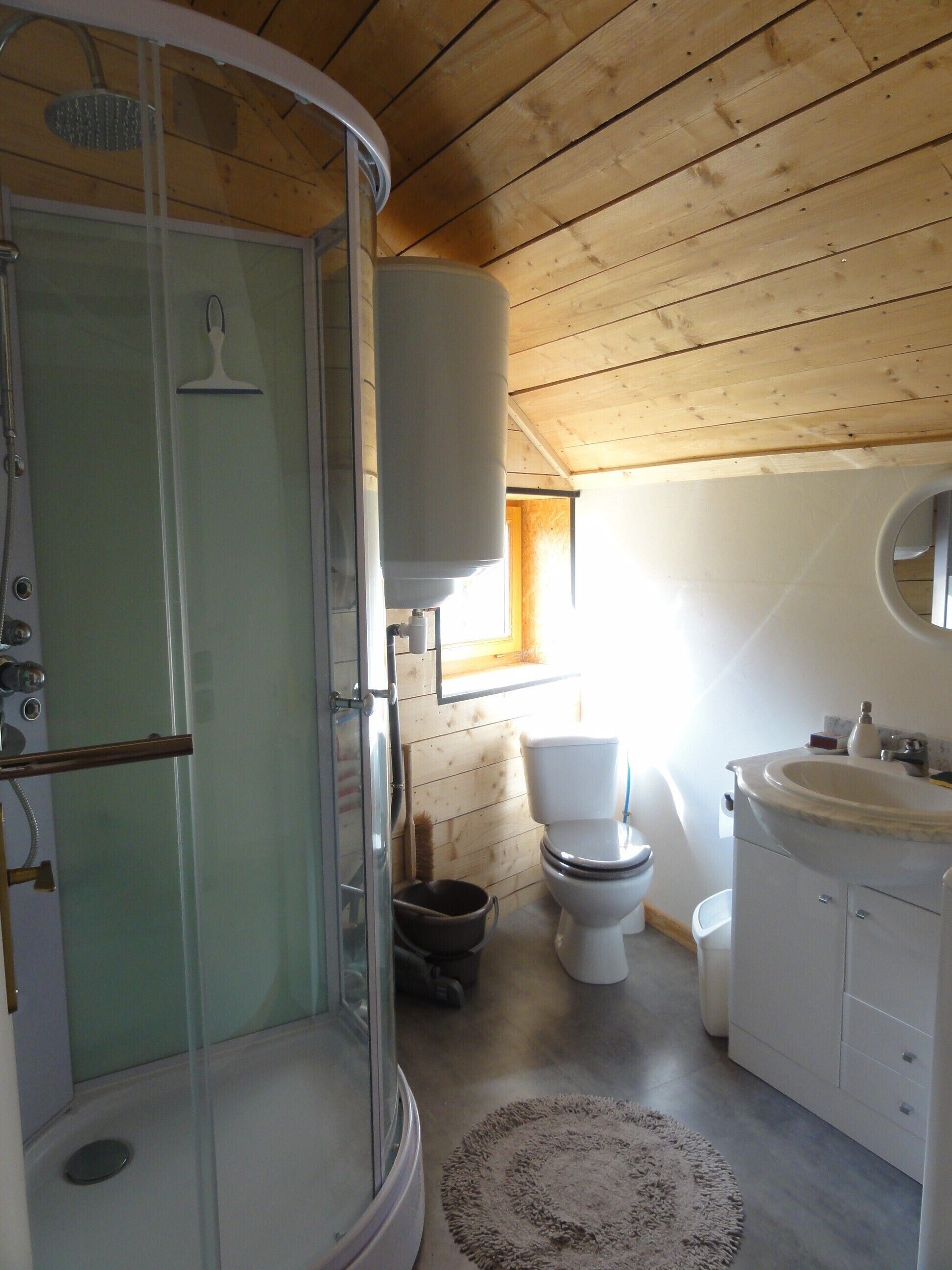 A bathroom with a glass-enclosed shower, a toilet, and a sink with a mirror.