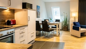 Ett modernt kök med en röd brödrost, en matplats med bord och stolar samt ett vardagsrum med en soffa och en lampa.