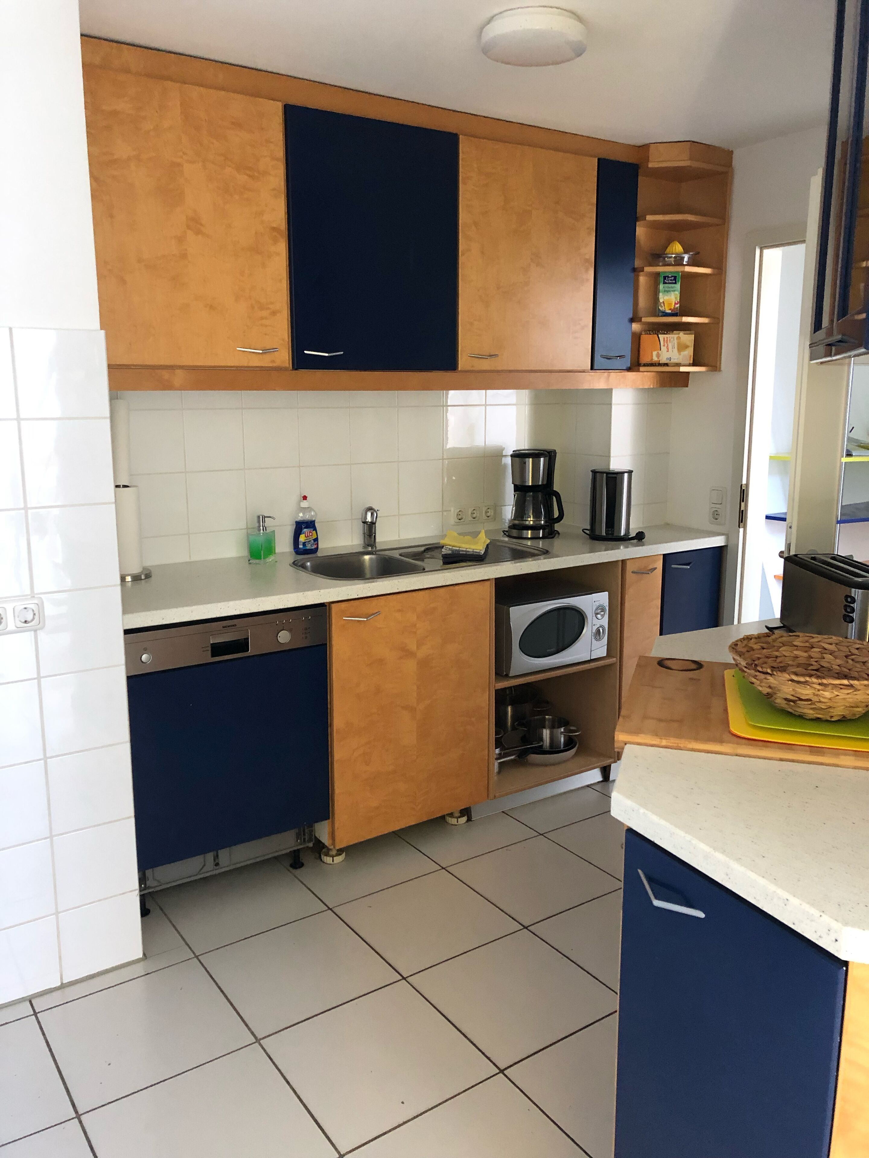Eine Küche mit Holzschränken, einem Geschirrspüler, einer Mikrowelle, einer Kaffeemaschine und einem Toaster.