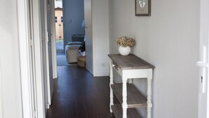 A hallway with a wooden table and a vase of dried flowers on a white wall.