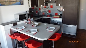 A modern kitchen with a dining area, red bar stools, and a large window with a cityscape view. - T1 bis, view Nive, heart of city, ideal for couple / small family, everything on foot! (Bayonne)