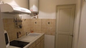Une cuisine compacte avec deux éviers, un four encastré et une porte blanche.