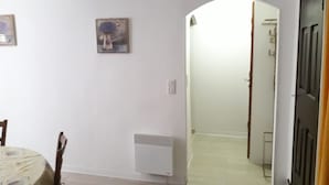 Un couloir avec un radiateur, une porte et un tableau encadré accroché au mur.