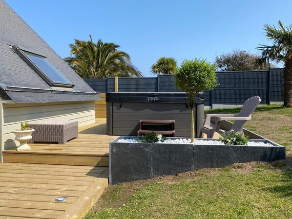A backyard with a wooden deck, a small shed, and a seating area with a chair and a table.