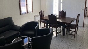Ein Essbereich mit Holztisch und Stühlen, einer Couch und einem kleinen runden Tisch.