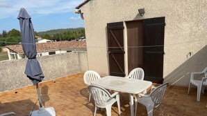 Eine Terrasse mit Tisch, Stühlen, Deckenventilator und Sonnenschirm.