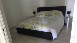 Een slaapkamer met een bed, twee nachtkastjes en een deur.