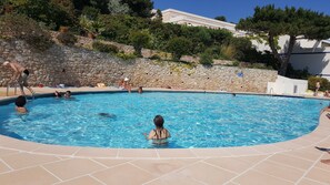 Uma piscina com paredes de pedra e um deck revestido com azulejos.