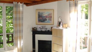 Une chambre à coucher avec un lit, une cheminée, un tableau au mur et une fenêtre avec des rideaux.