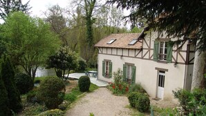 Une maison traditionnelle à colombages, avec un chemin de gravier menant à un espace patio.