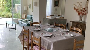 Un coin repas avec une table dressée pour quatre personnes, entourée de chaises en bois dotées de coussins à carreaux.