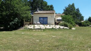 A house with a tiled roof, a large window, and a patio area with outdoor furniture. - Very nice Mazet with pool and panoramic views of the Cevennes (Saint-Privat-de-Champclos)