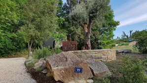 A garden with a gravel path, large rocks, a stone wall, and a sign reading "Lo Muzzo". - Very nice Mazet with pool and panoramic views of the Cevennes (Saint-Privat-de-Champclos)