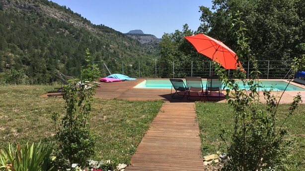 A wooden deck leading to a pool area with lounge chairs and an umbrella. - Large villa with swimming pool in a peaceful setting in the Baronnies provençales (Verclause)