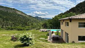 A house with a pool, surrounded by a grassy yard and a forested hillside. - Large villa with swimming pool in a peaceful setting in the Baronnies provençales (Verclause)