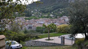 A residential area with stone walls, a paved pathway, and a car parked in the foreground.