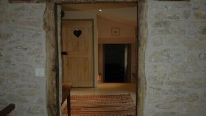 Ein Flur mit Steinwänden, der zu einem Raum mit einer Holztür und einer herzförmigen Dekoration führt.