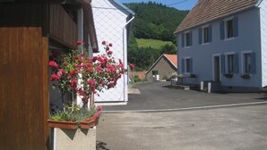 Een rustige straat met witte gebouwen, een houten omheining en een bloembak met roze bloemen.