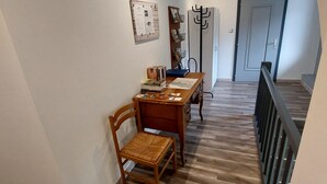 Een hal met een houten vloer, een eettafel met stoelen, een kapstok en een deur.