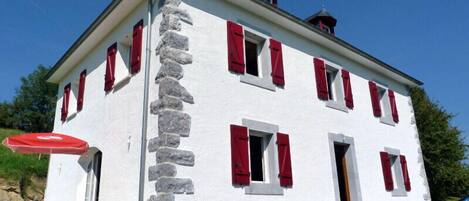 A two-story building with red shutters and a stone column.