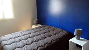Une chambre à coucher avec un lit, une table de chevet, une lampe et une fenêtre.