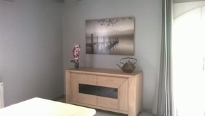 Une pièce d’angle avec un meuble en bois, un tableau accroché au mur et une petite table.