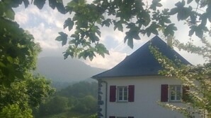Une maison à deux étages avec un toit en pente, une allée en gravier et une voiture garée.