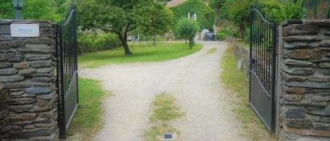A gravel path leading to a stone-walled gate with a sign reading "Clevacces."