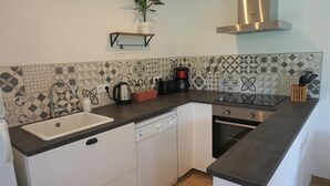 Een keuken met een vaatwasser, fornuis, spoelbak en koffiezetapparaat.