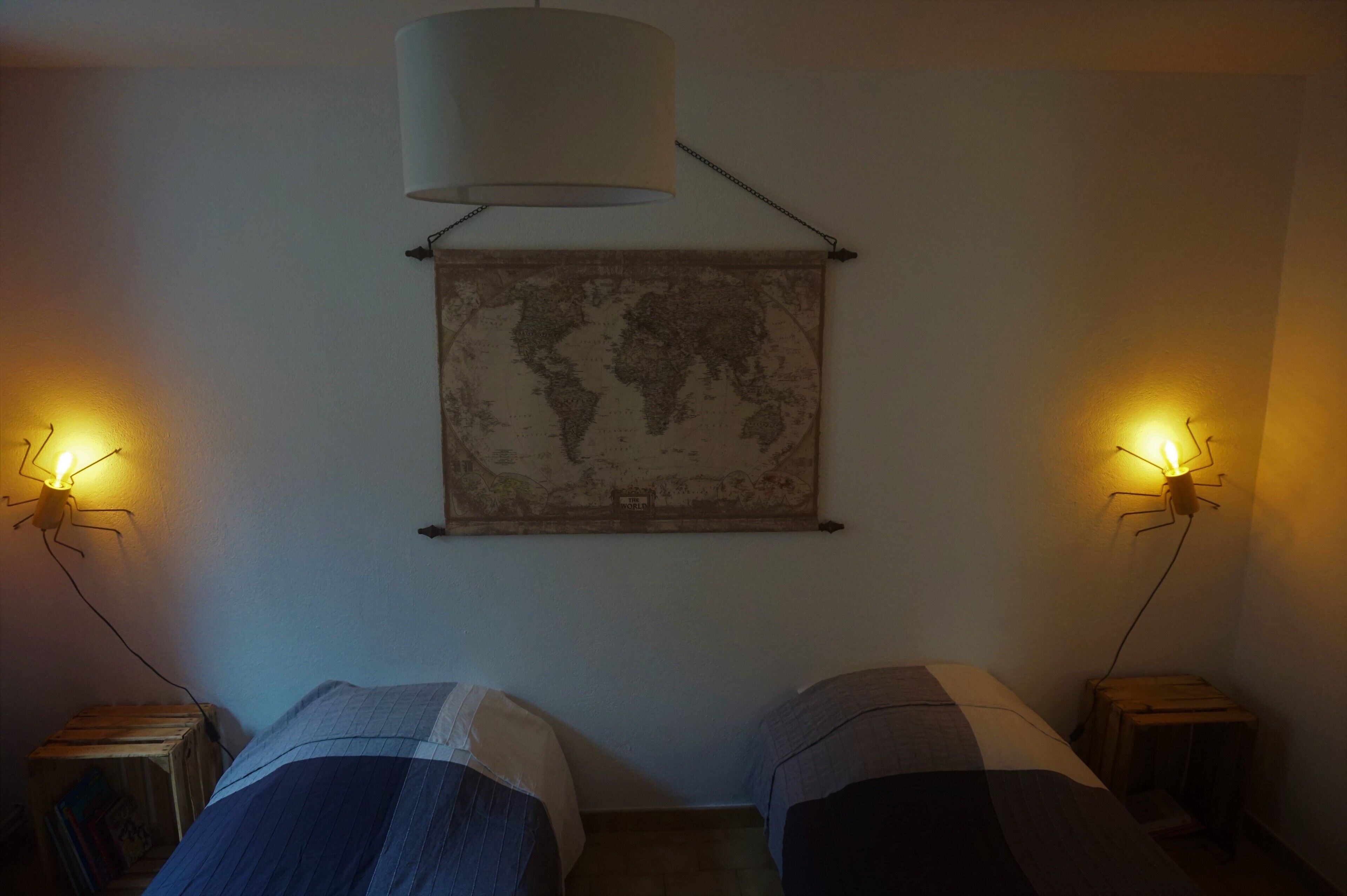 Ein Zimmer mit zwei Betten, einer Weltkarte an der Wand und zwei Wandlampen.