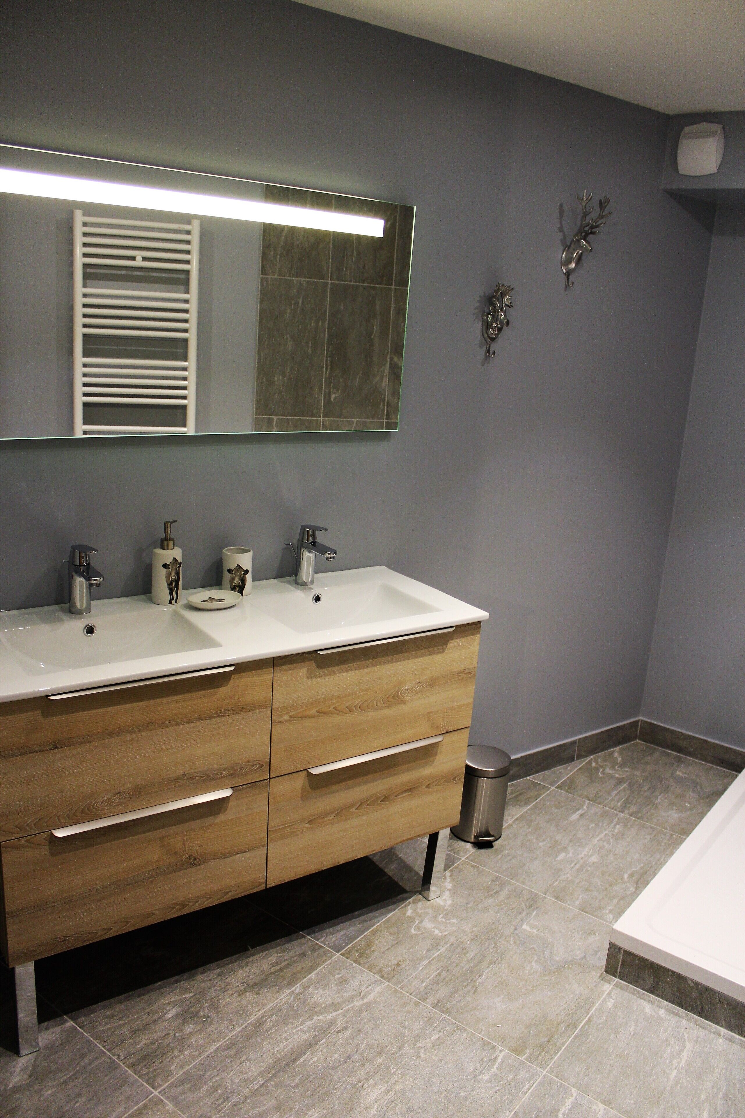 Une salle de bain moderne avec deux lavabos, un grand miroir et un meuble-lavabo en bois.