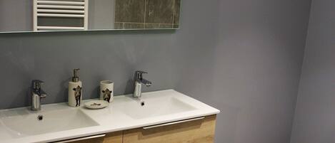 Une salle de bain moderne avec deux lavabos, un grand miroir et un meuble-lavabo en bois.