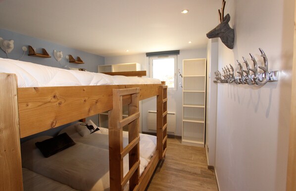 Quarto com beliche, cabeceira de madeira, decoração de cabeça de veado e prateleira com chifres.