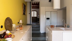 Eine Küche mit gelber Wand, einer Treppe zu einem Essbereich und einem Kühlschrank.